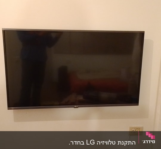 טלוויזיה תלויה על הקיר עם שקע חשמל